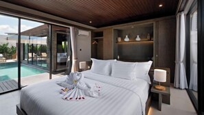 A modern hotel room with a large bed, a bedside table with a lamp, a built-in shelf with decorative items, and a view of a swimming pool. - D'Padi Villa Canggu (Bali)