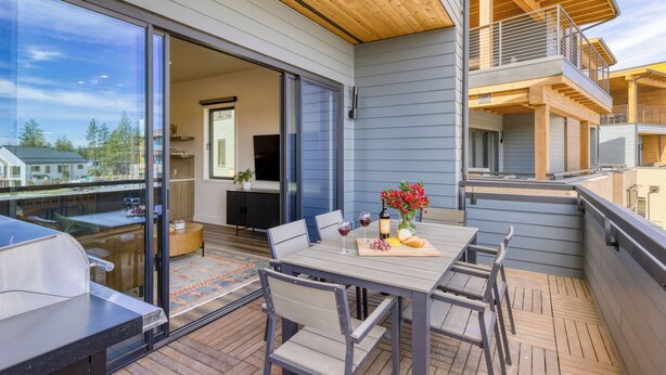 Eine moderne Terrassengestaltung mit Esstisch für zwei Personen, Grill und Blick auf die umliegende Nachbarschaft.