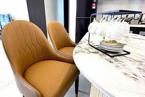 Cozinha moderna com bancada de mármore, duas cadeiras de couro marrom e um escorredor de louça com pratos.