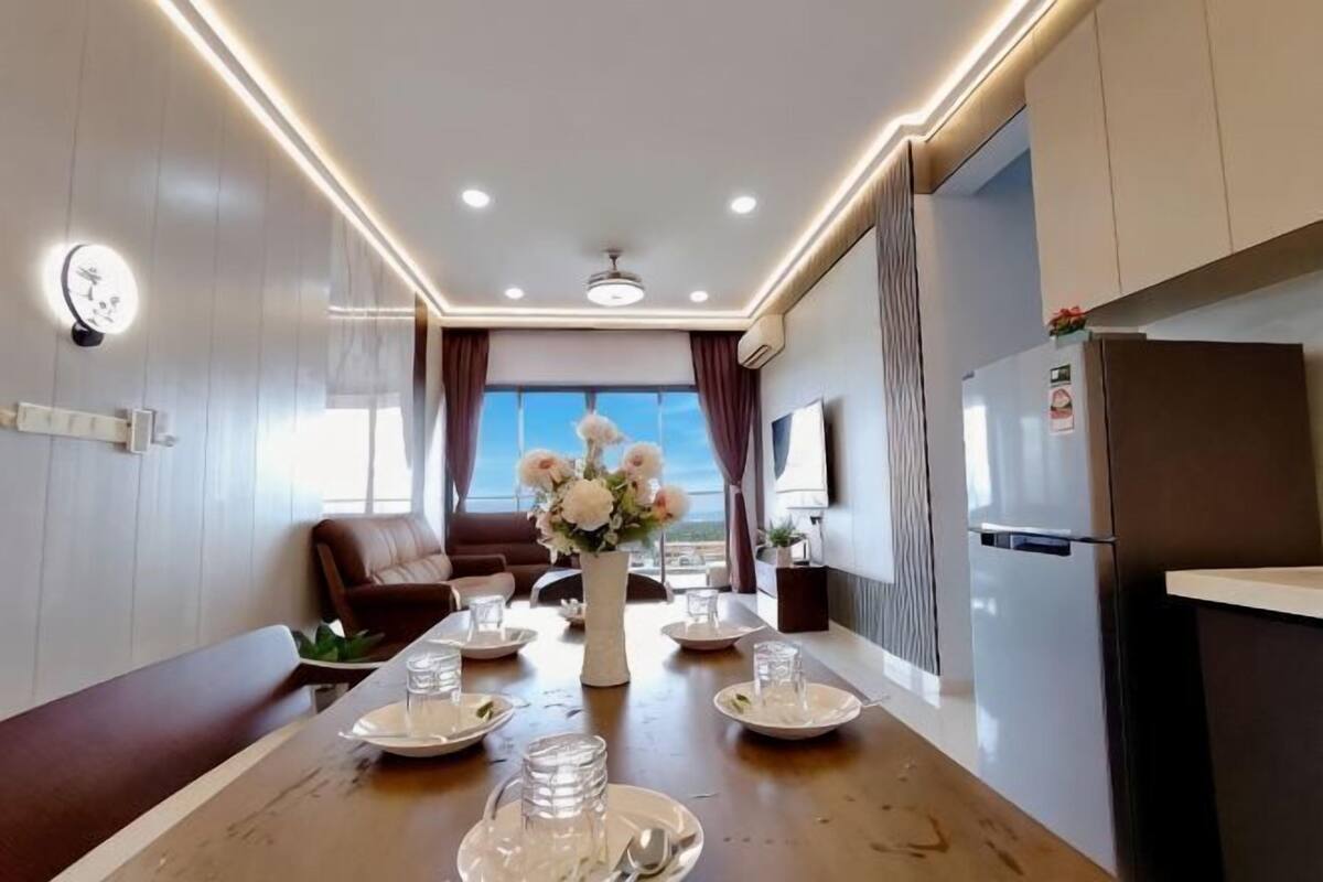 A modern kitchen with a dining area, a refrigerator, and a view of the outdoors.