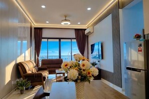 Un salon moderne avec un canapĂ©, une table basse, un vase de fleurs et une grande fenĂȘtre donnant sur un beau paysage.