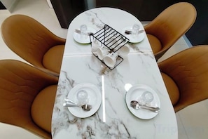 A dining table with four chairs, a tray with cutlery, and a glass of water.