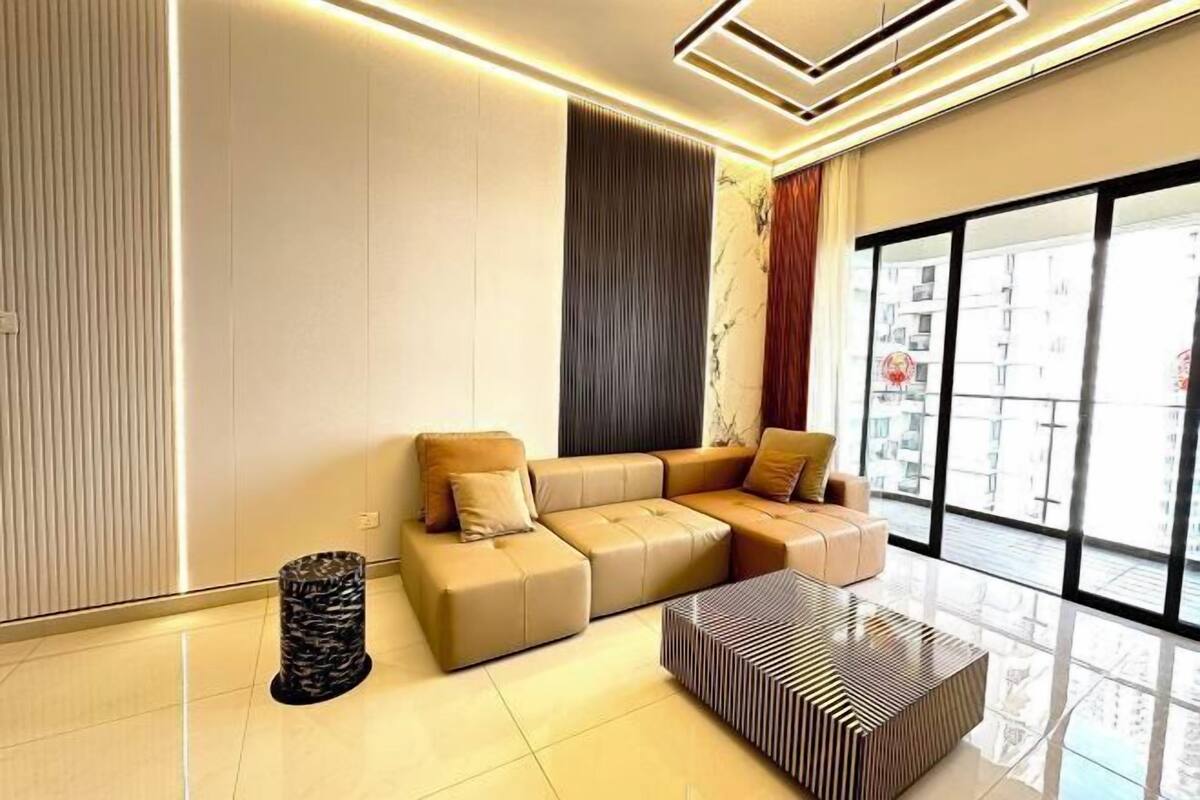 A modern living room with a sectional sofa, a patterned coffee table, and a large window offering a city view.