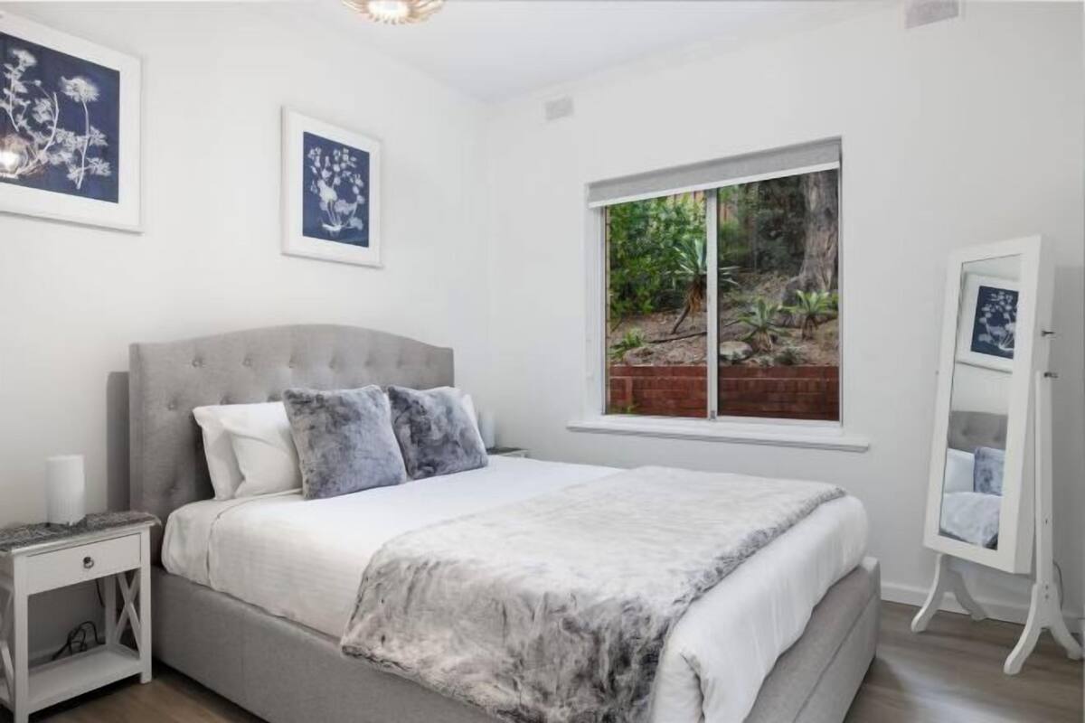 A bedroom with a bed, a nightstand, a dresser, and framed pictures on the wall.