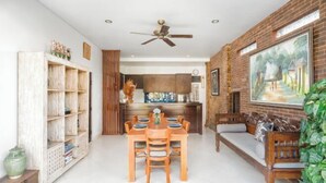 A spacious living area with a dining table, wooden chairs, a sofa, and a ceiling fan. - Umah Bali Villa (Bali)