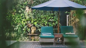 A poolside area with two green lounge chairs, a small table, and a blue umbrella. - Umah Bali Villa (Bali)