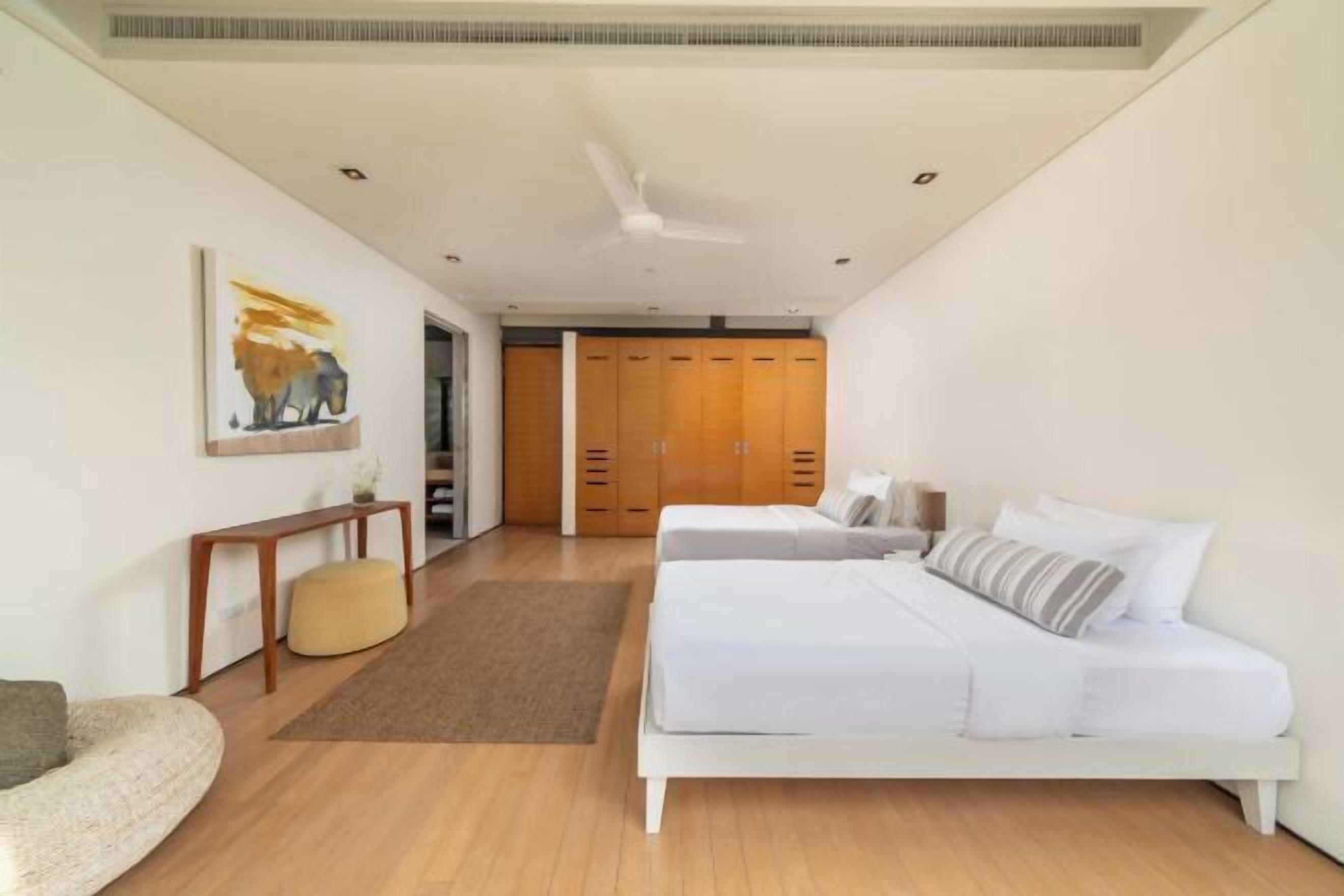 Ein Schlafzimmer mit Bett, Nachttischen, Deckenventilator und Kleiderschrank.