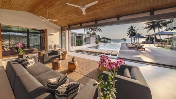A modern living room with a large sofa, a coffee table, and a view of an infinity pool and ocean. - Sava Villa 2 Villa Amarelo (Takua Thung)