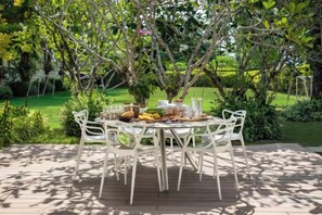 An outdoor dining area with a round table and chairs, surrounded by greenery and trees. - Sava Villa 2 Villa Amarelo (Takua Thung)
