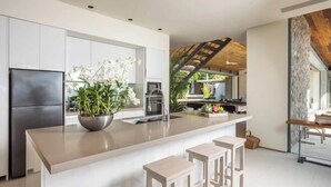 A modern kitchen with a large island, bar stools, and a refrigerator. - Sava Villa 2 Villa Amarelo (Takua Thung)
