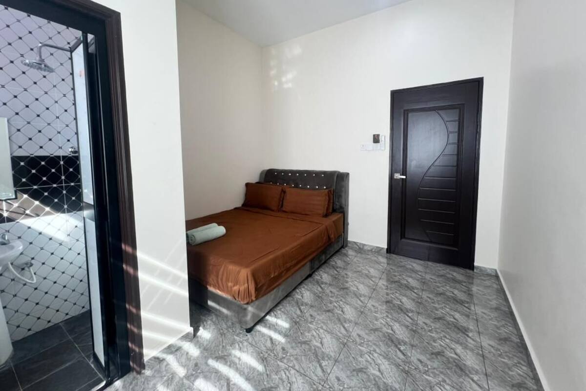 A bedroom with a bed, a door, and a bathroom visible through a glass door.