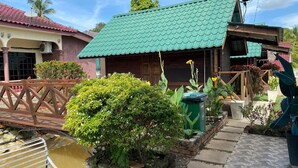 A traditional house with a green tiled roof, a wooden porch, and a small garden area with a water feature. - Capital O 91227 Chalet D'bendang Mak Teh (Pendang)