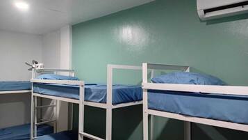 A dormitory room with bunk beds, a ceiling light, and an air conditioning unit.