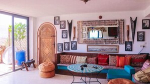 Uma sala de estar com um espelho grande, um sofá, uma mesa redonda e uma porta de madeira.