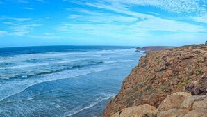 Paisagem costeira com falésias rochosas e o oceano.