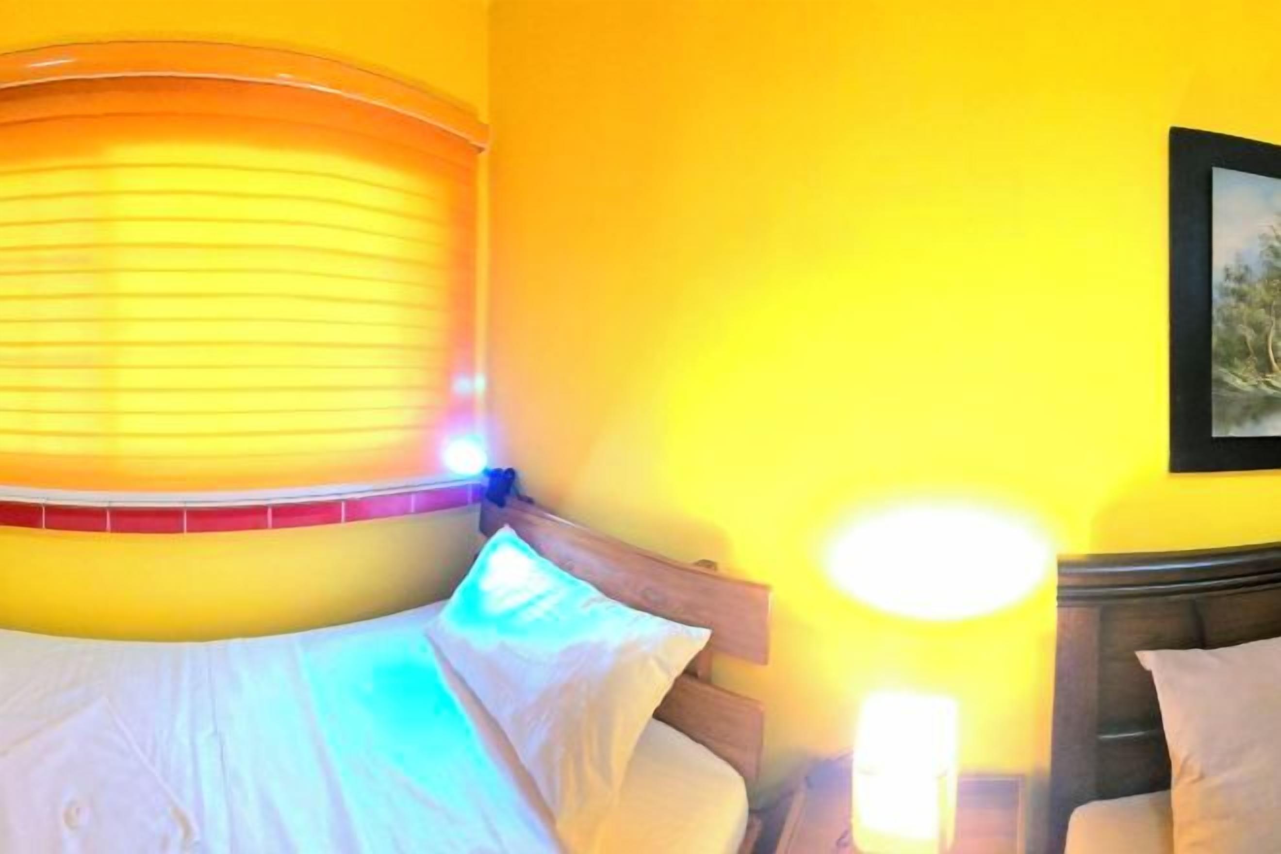A room with a bed, a nightstand, and a wall-mounted lamp.