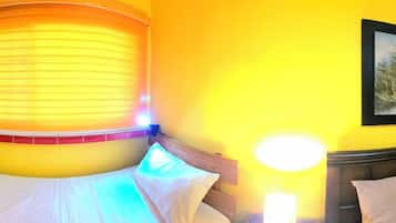 A room with a bed, a nightstand, and a wall-mounted lamp.
