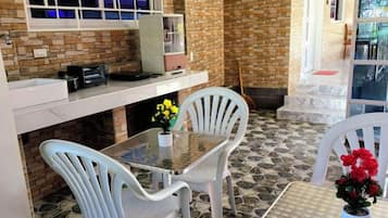 A patio area with a table and chairs, a small kitchen setup, and a brick wall.
