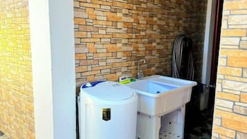 A bathroom with a brick wall, a white sink, and a white toilet.