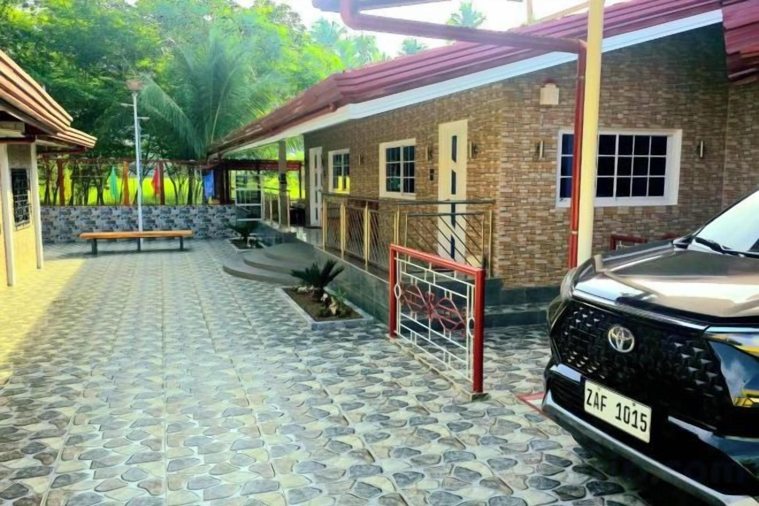 Un cortile lastricato con una panchina, un'auto e un edificio con tetto rosso.