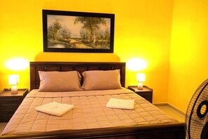 A bed with a headboard, two bedside tables with lamps, and a painting above the bed. - Jenessa's Executive-Suite near Lanuza Surf Bay (Madrid)