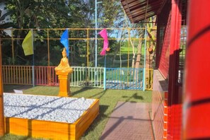 A fenced outdoor area with a play structure, a small garden bed, and a pathway. - Jenessa's Executive-Suite near Lanuza Surf Bay (Madrid)