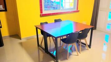 Un comedor con una mesa y sillas, un ventanal con vistas y una pared amarilla.