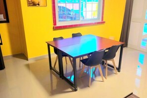 A dining area with a table and chairs, a window with a view, and a yellow wall. - Jenessa's Executive-Suite near Lanuza Surf Bay (Madrid)