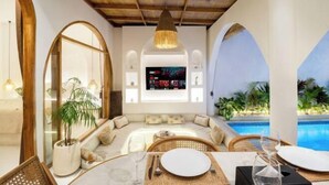 A modern, well-lit lounge area with a pool view, comfortable seating, and a television screen. - Brand New Villa 2Br with Private Pool Near Seminyak by BaliSuperHost (Bali)