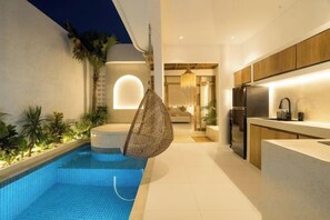 Cocina moderna con refrigerador integrado, una cesta colgante y un área de piscina con jacuzzi.