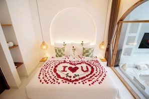 Una cama con un arreglo de flores rojas con forma de corazón y un diseño que dice 'I ♥ U' en la colcha.