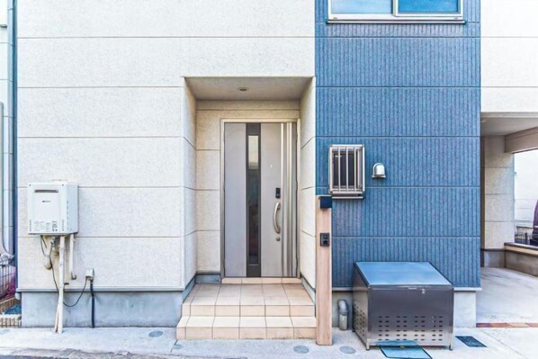 A building entrance with a door, a small outdoor seating area, and a utility box. - Third Place Tokyo - Aoto - (Tokyo)