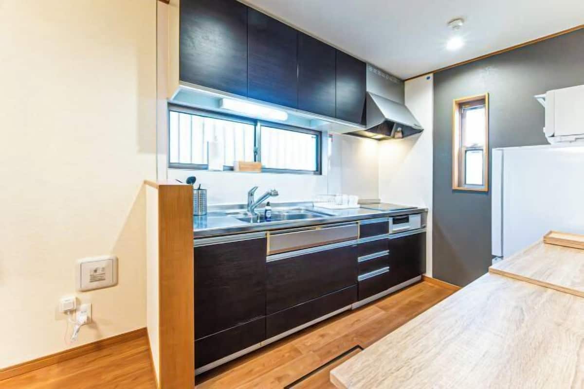 A modern kitchen with dark cabinetry, a stainless steel sink, and a window above the counter.