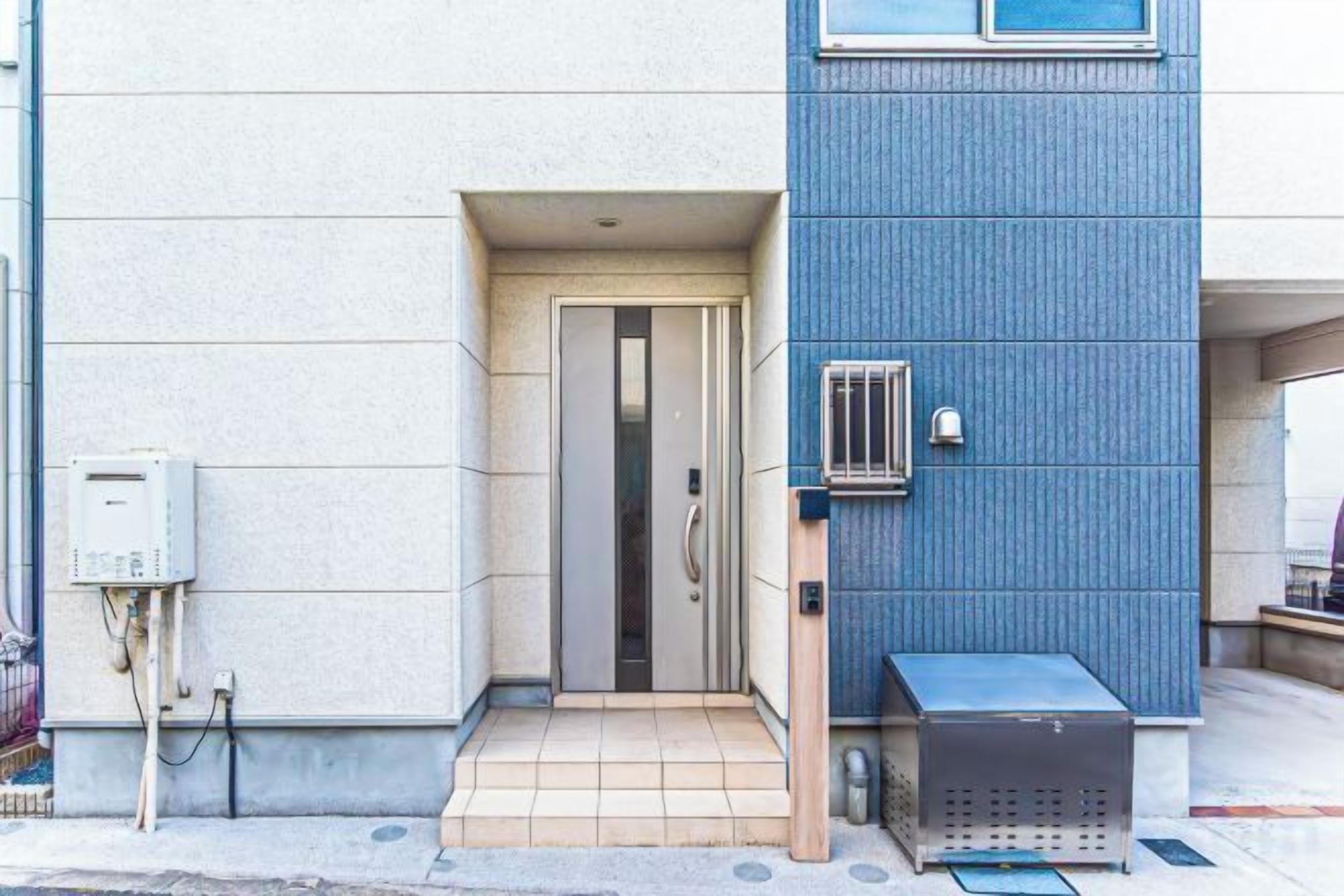 A building entrance with a door, a mailbox, and a small outdoor seating area.