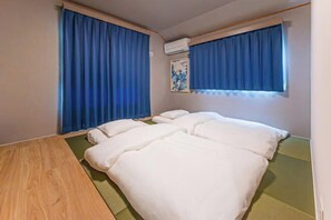 A room with two beds, a wooden floor, and blue curtains. - Third Place Tokyo - Aoto - (Tokyo)