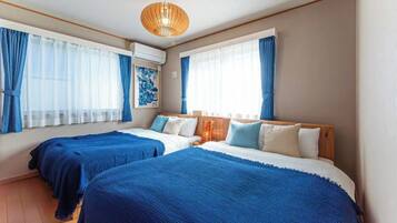 A hotel room with two beds, a wooden headboard, a ceiling light, and a window with curtains.
