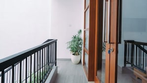 A balcony with a potted plant, a wooden door, and a black railing. - The Lavana Nakula Villa Kuta Sunset (Bali)