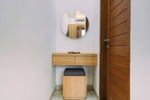 A small bathroom with a wooden vanity, a round mirror, and a wooden stool. - The Lavana Nakula Villa Kuta Sunset (Bali)