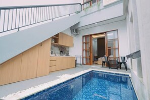 A modern apartment with a kitchen, dining area, and a small pool. - The Lavana Nakula Villa Kuta Sunset (Bali)