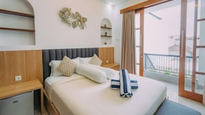 A hotel room with a bed, a small desk, a wardrobe, and a balcony with a view. - The Lavana Nakula Villa Kuta Sunset (Bali)