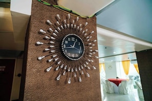 A wall clock with a sunburst design, mounted on a textured wall.