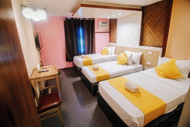 A hotel room with three beds, a desk, and a chair.