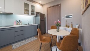Een moderne keuken met grijze kastjes, een roestvrijstalen koelkast en een ronde tafel met vier stoelen.