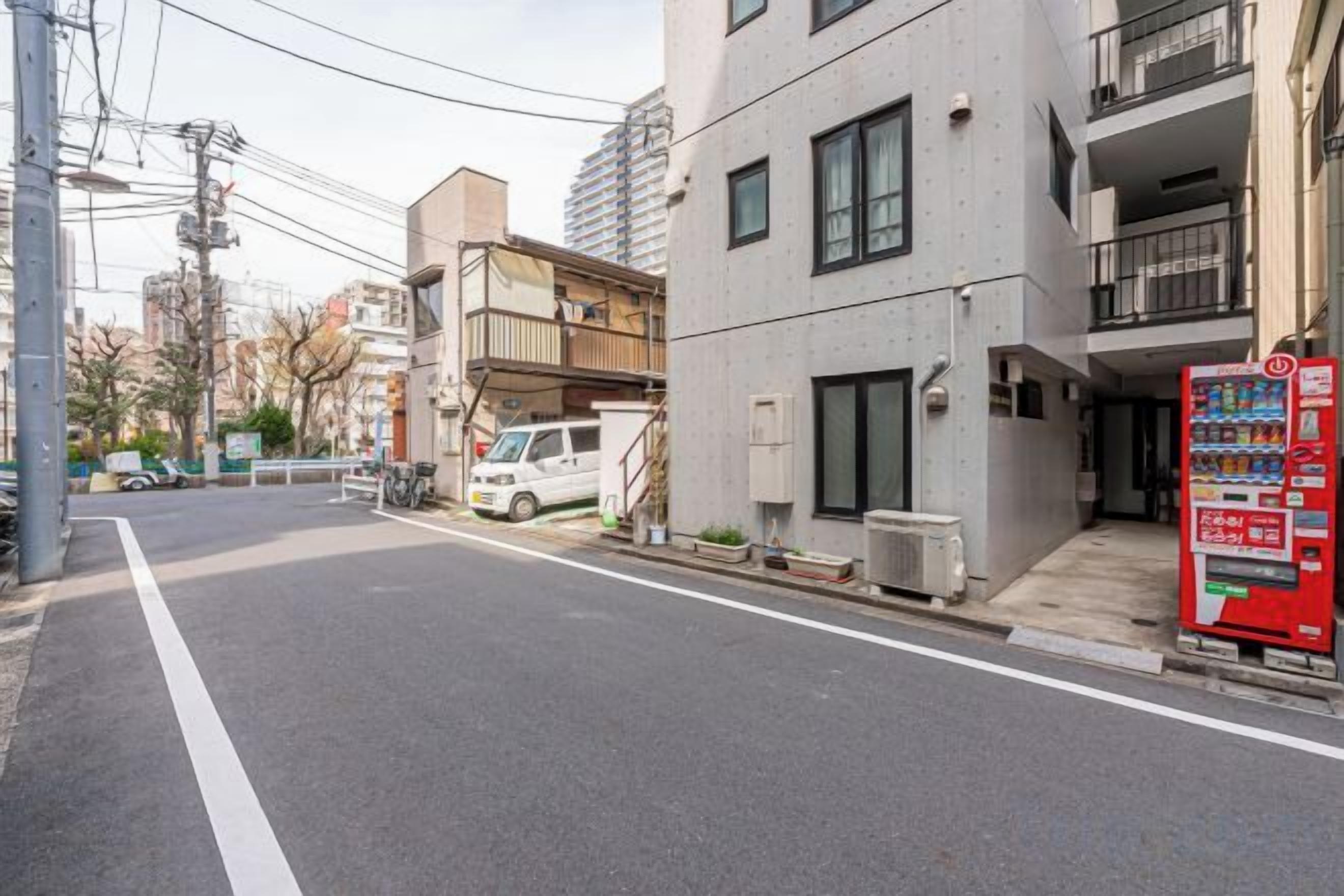 A street with a building that has a vending machine on the sidewalk.