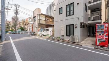 A street with a building that has a vending machine on the sidewalk.