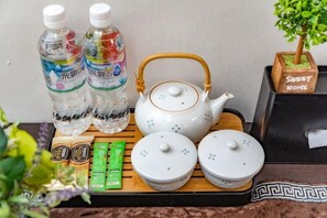 Un plateau avec une théière, deux bouteilles, deux récipients et une petite plante.