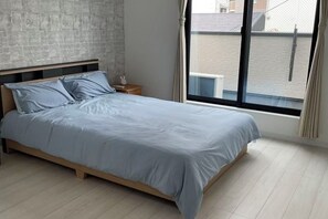 Um quarto com uma cama, mesa de cabeceira e janela com cortinas.