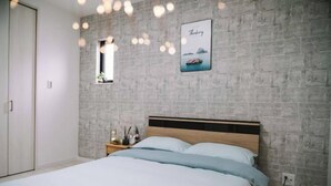 A bedroom with a bed, a nightstand, a small window, and a wall-mounted picture. - youmeiyado kohama (Osaka)