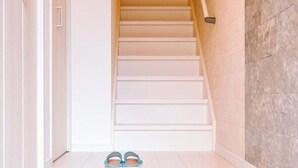 A staircase with white steps and a wooden handrail, leading to a door. - youmeiyado kohama (Osaka)