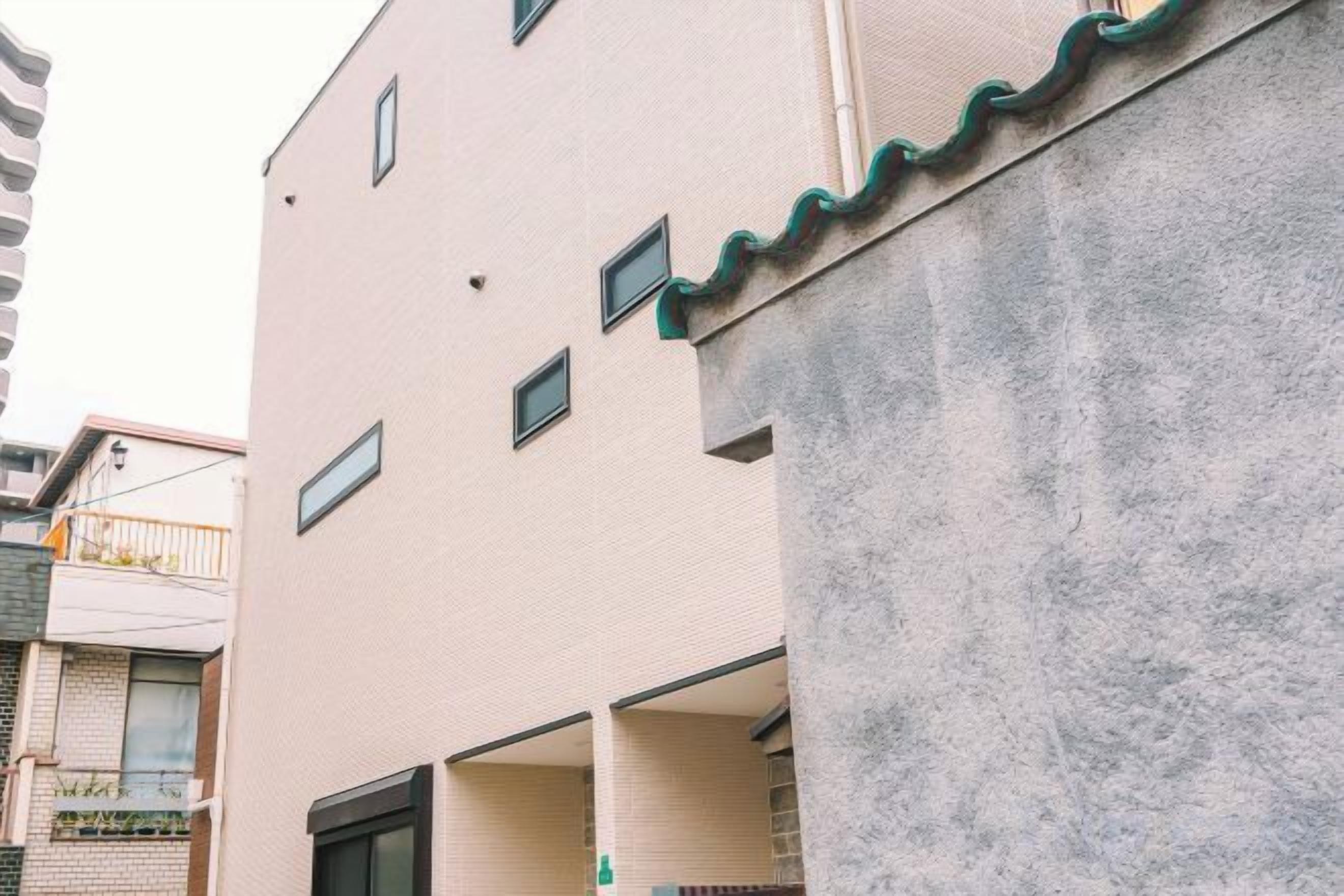 A multi-story building with balconies, a concrete wall, and a visible entrance.